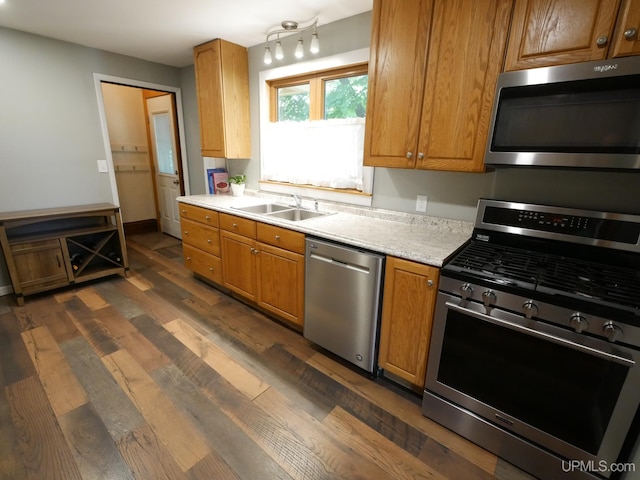 kitchen with stainless steel appliances, dark wood-style flooring, a sink, and brown cabinets