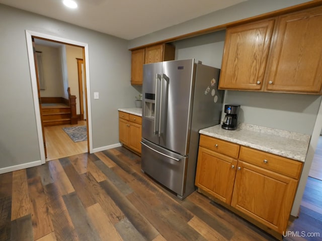 kitchen with brown cabinetry, dark wood finished floors, and stainless steel fridge with ice dispenser