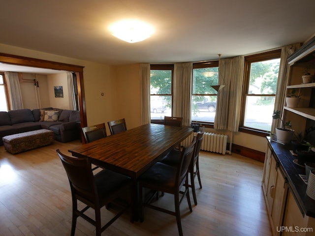 dining space featuring light wood-type flooring, baseboards, and radiator heating unit