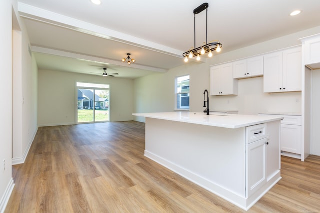 kitchen featuring a center island with sink, a sink, a wealth of natural light, and white cabinetry