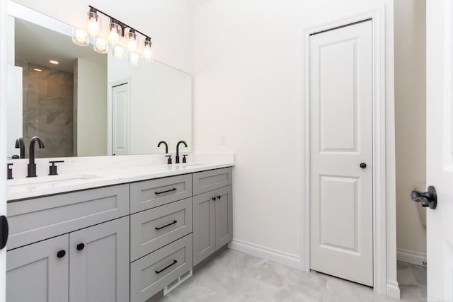 bathroom featuring marble finish floor, a sink, baseboards, and double vanity