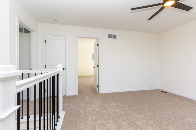 unfurnished room featuring light colored carpet, visible vents, ceiling fan, and baseboards