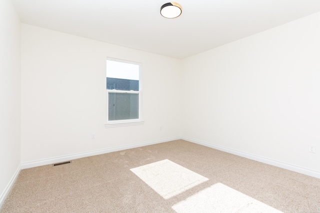 carpeted spare room featuring baseboards and visible vents