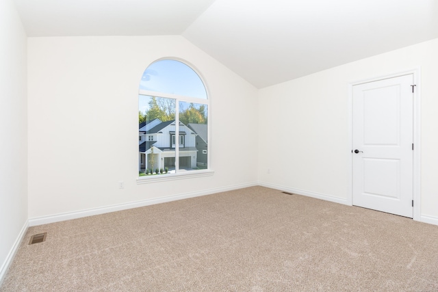 carpeted empty room featuring lofted ceiling, visible vents, and baseboards