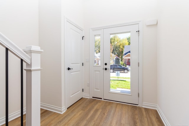 doorway featuring stairs, light wood-style flooring, and baseboards