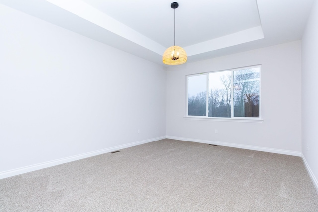 empty room featuring carpet floors, baseboards, visible vents, and a tray ceiling