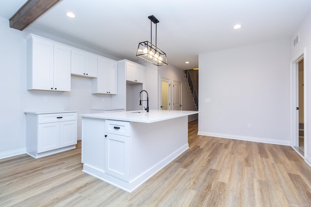 kitchen with recessed lighting, light wood-style flooring, white cabinetry, a sink, and a kitchen island with sink