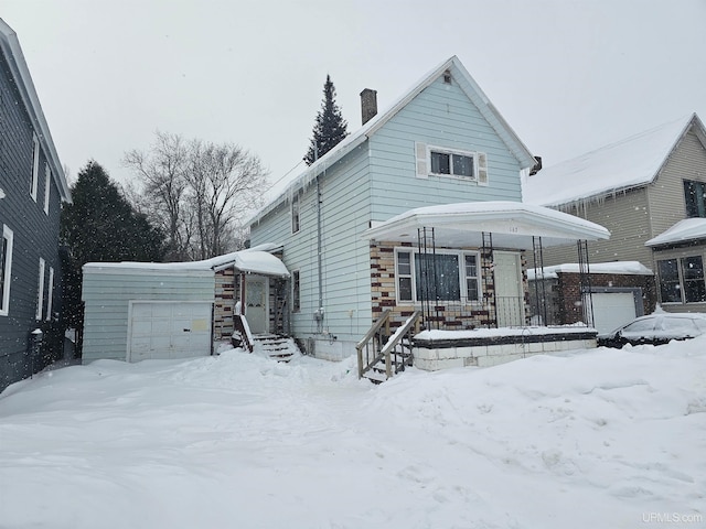 view of front facade with an attached garage, a chimney, and an outdoor structure