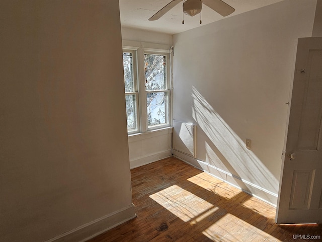 spare room featuring a ceiling fan, wood-type flooring, and baseboards