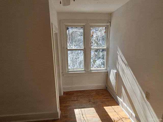 unfurnished room with a wealth of natural light, dark wood finished floors, and baseboards