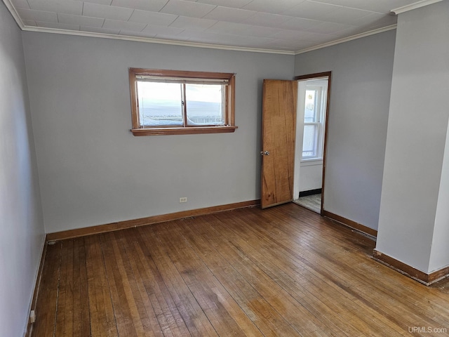 empty room with crown molding, baseboards, and hardwood / wood-style floors