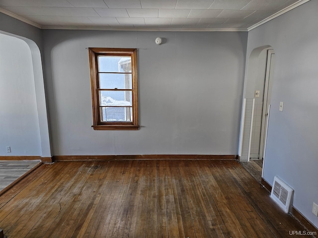 empty room with arched walkways, ornamental molding, hardwood / wood-style flooring, and visible vents