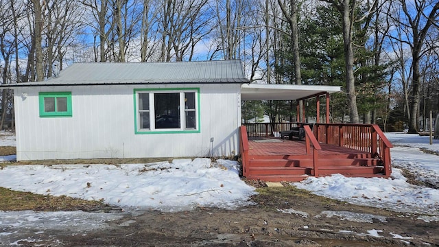 snow covered property featuring metal roof and a wooden deck