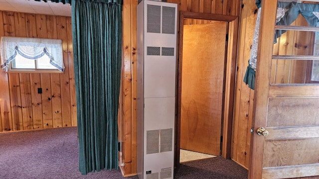 interior space featuring carpet floors, a heating unit, and wooden walls