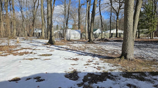 yard covered in snow featuring a greenhouse and an outbuilding