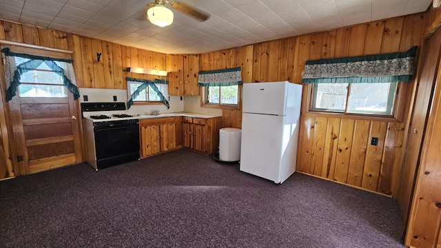 kitchen featuring gas range oven, dark colored carpet, light countertops, and freestanding refrigerator