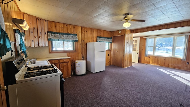 kitchen featuring white appliances, wood walls, and plenty of natural light