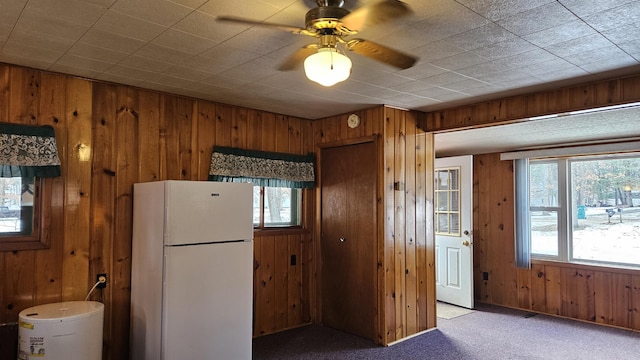 kitchen with wood walls, carpet, ceiling fan, and freestanding refrigerator