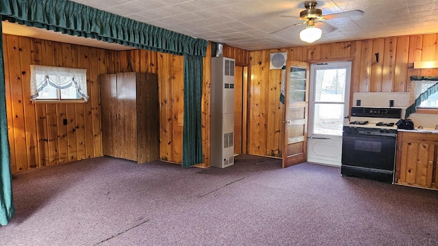 kitchen with wooden walls, dark carpet, and gas stove