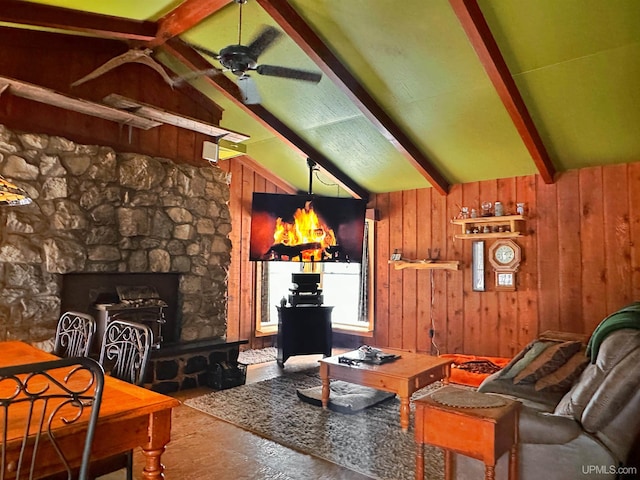 living area with lofted ceiling with beams, ceiling fan, a fireplace, and wooden walls