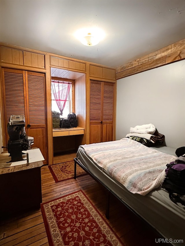 bedroom with hardwood / wood-style floors and two closets