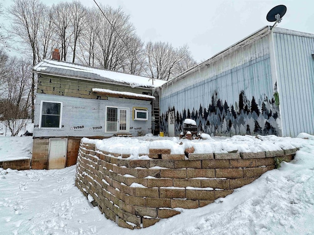 snow covered rear of property with a chimney