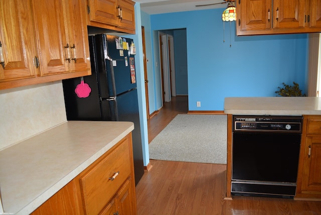 kitchen featuring brown cabinetry, ceiling fan, wood finished floors, light countertops, and black appliances