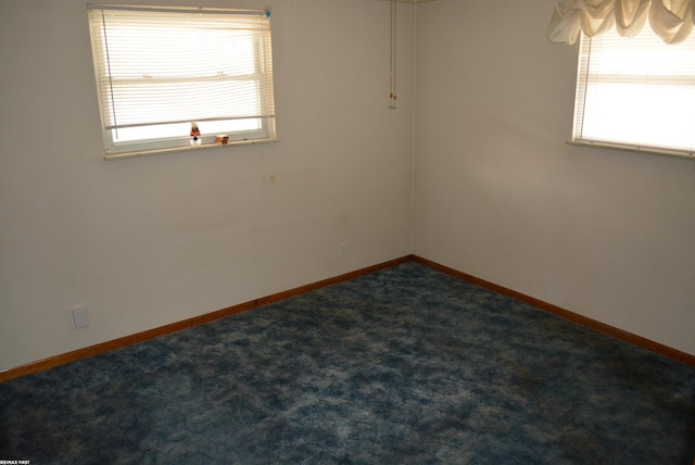 empty room featuring baseboards and dark carpet