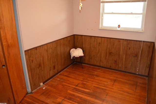 unfurnished room featuring hardwood / wood-style floors, wainscoting, and wooden walls