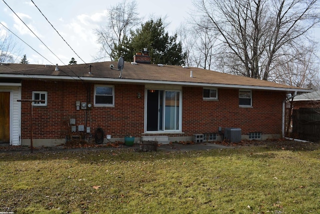 back of house featuring brick siding, a chimney, a lawn, entry steps, and cooling unit