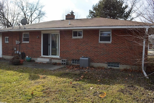 back of property with entry steps, brick siding, a chimney, and central air condition unit