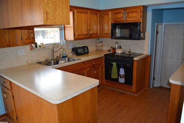 kitchen featuring black appliances, brown cabinetry, a sink, and light countertops