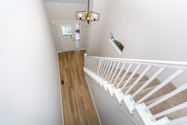 stairs featuring a notable chandelier and wood finished floors