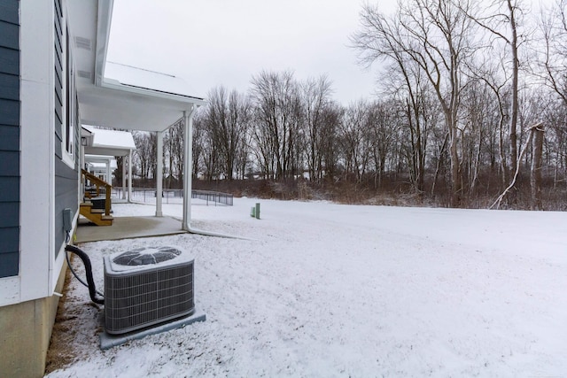 snowy yard featuring stairs and central AC