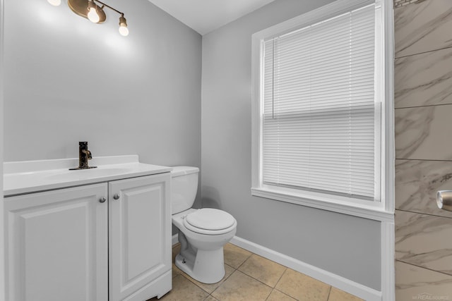 half bathroom featuring toilet, tile patterned flooring, baseboards, and vanity