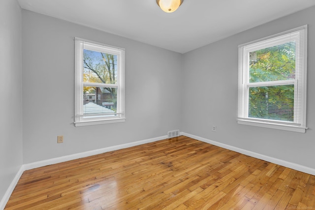 unfurnished room featuring light wood finished floors, visible vents, and baseboards