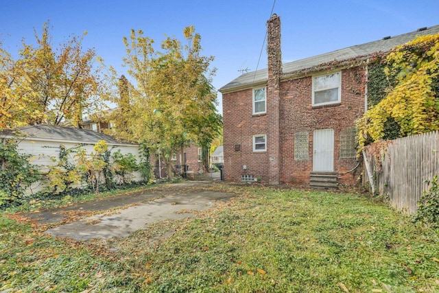 back of house with a yard, entry steps, brick siding, and fence