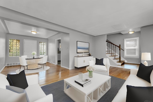 living room featuring stairs, wood finished floors, visible vents, and baseboards