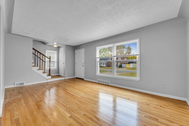 unfurnished living room with stairs, wood finished floors, and visible vents