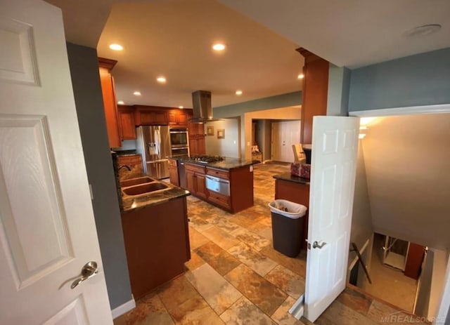 kitchen featuring island exhaust hood, a warming drawer, dark countertops, appliances with stainless steel finishes, and a sink