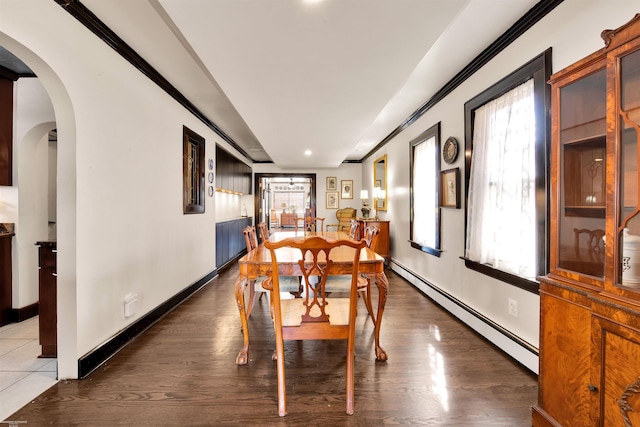 dining area with a baseboard heating unit, arched walkways, baseboards, and wood finished floors