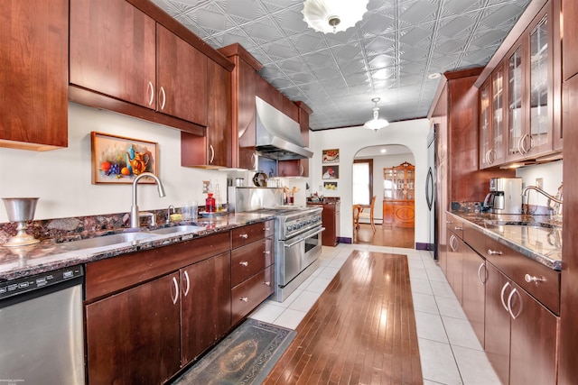 kitchen with arched walkways, an ornate ceiling, appliances with stainless steel finishes, extractor fan, and a sink