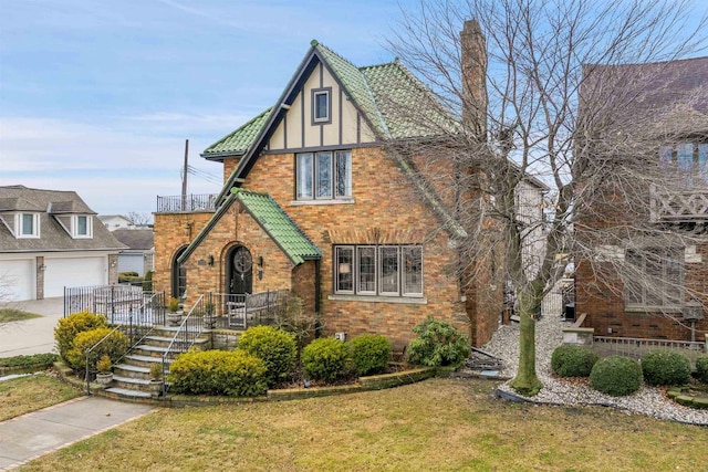 tudor-style house with a front yard, brick siding, driveway, and stucco siding