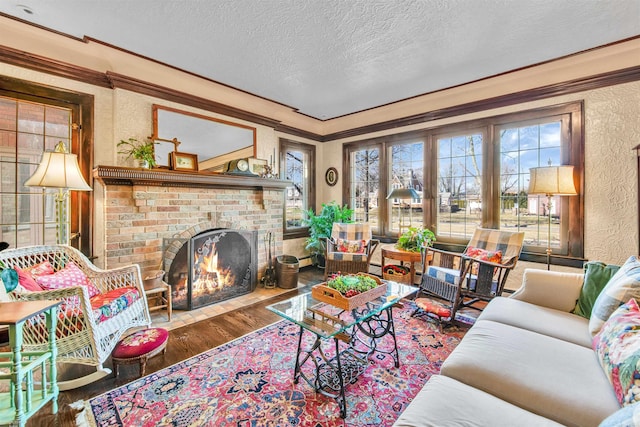 living area with a textured ceiling, a textured wall, a fireplace, wood finished floors, and crown molding