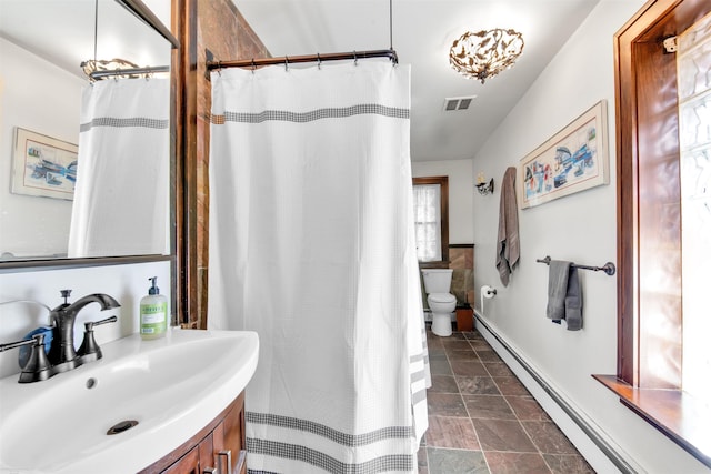 bathroom with visible vents, toilet, baseboard heating, stone finish floor, and vanity