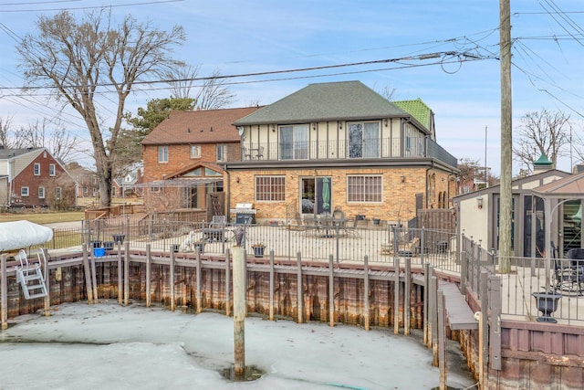 back of property with brick siding, fence, and a balcony