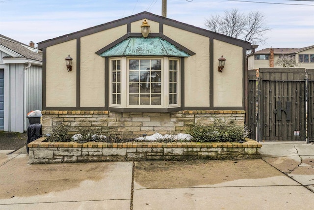 exterior space featuring stone siding, fence, and stucco siding