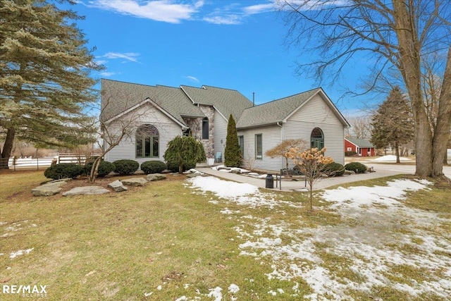 view of front of property with a yard, roof with shingles, and fence