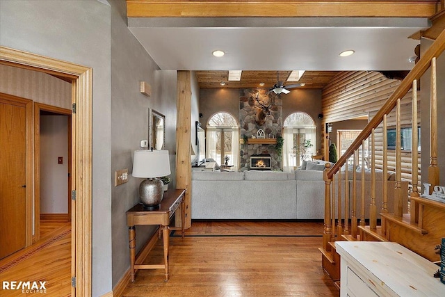 living room with baseboards, light wood-style flooring, ceiling fan, stairway, and a fireplace