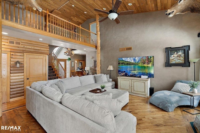 living room featuring visible vents, wood ceiling, wood-type flooring, stairway, and a high ceiling